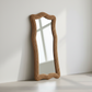 Decorative mirror with wavy brown frame on a white wall