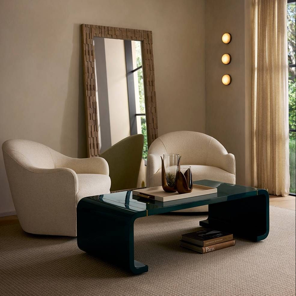 Modern living room with beige armchairs, a dark coffee table, and decorative elements.