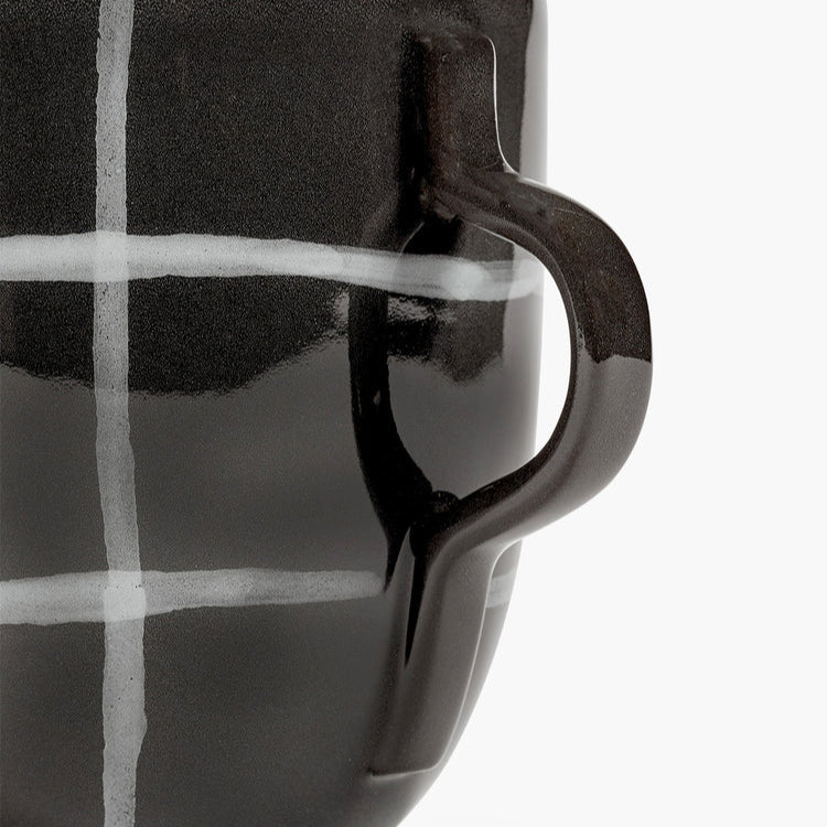 Black and white checkered mug with a handle on a light gray background
