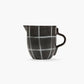 Black and white checkered ceramic pitcher on a white background