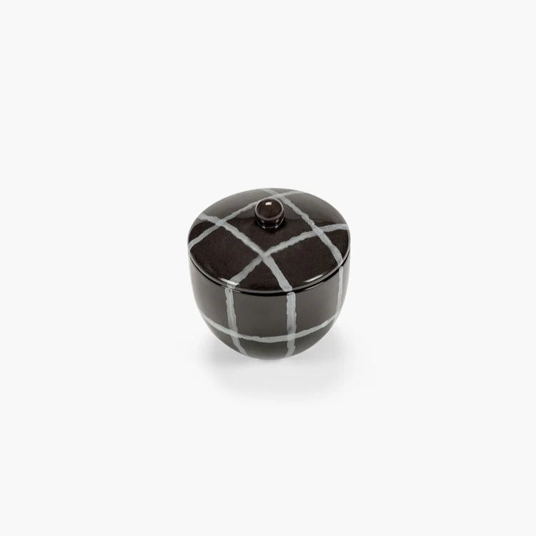Small black and white ceramic jar on a white background
